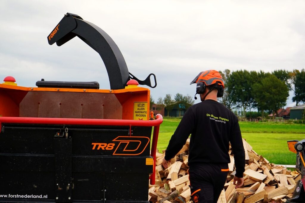 Boomverzorger loopt langs de versnipperaar naar het haardhout