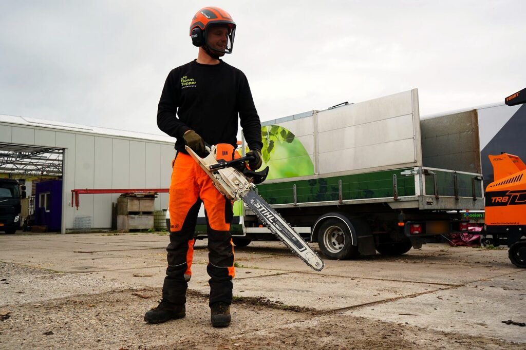 Boomverzorger van De Boom Topper met motorzaag op de werf